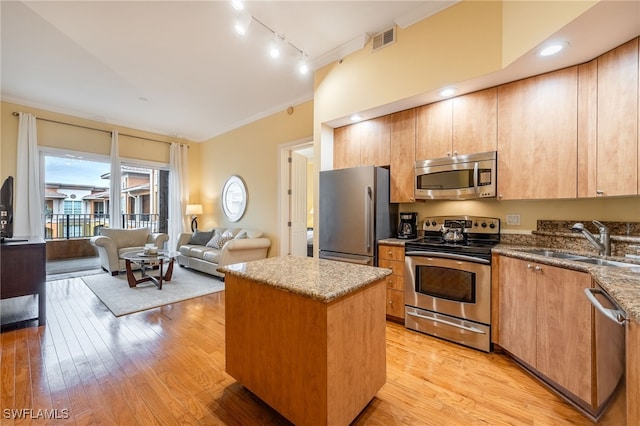 kitchen featuring appliances with stainless steel finishes, sink, light hardwood / wood-style floors, and a center island