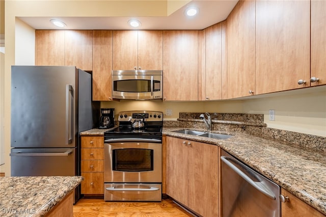 kitchen featuring light wood-type flooring, sink, stone countertops, and stainless steel appliances