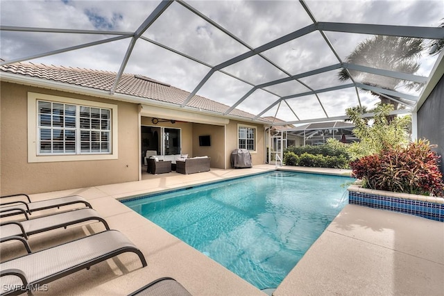 view of pool with glass enclosure, outdoor lounge area, pool water feature, and a patio