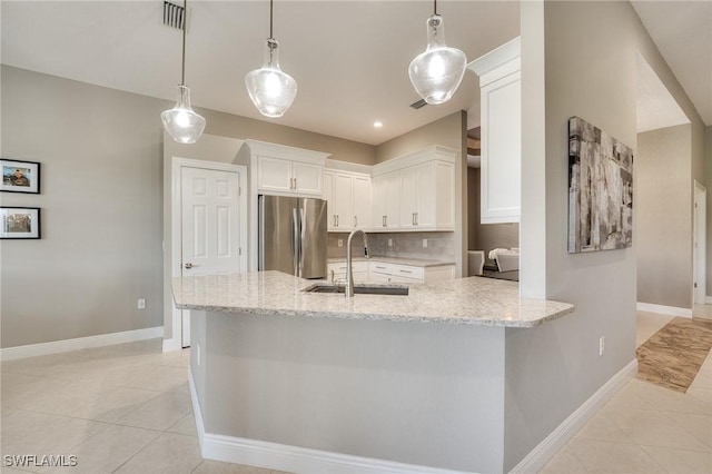 kitchen featuring stainless steel fridge, sink, white cabinetry, and pendant lighting