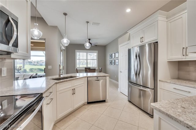 kitchen with white cabinets, appliances with stainless steel finishes, decorative backsplash, sink, and ceiling fan