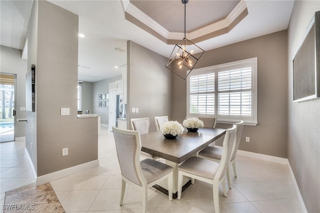 dining room with light tile patterned flooring, ornamental molding, a tray ceiling, and a notable chandelier