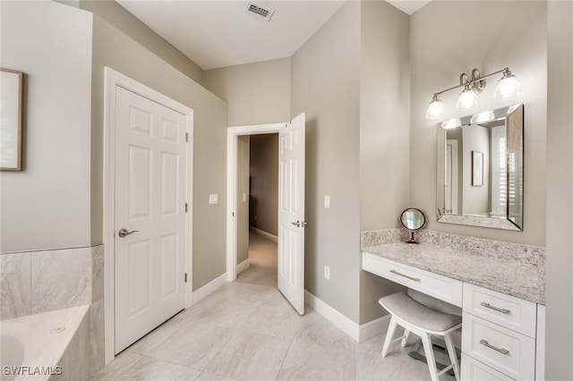 bathroom with a relaxing tiled tub, vanity, and tile patterned flooring