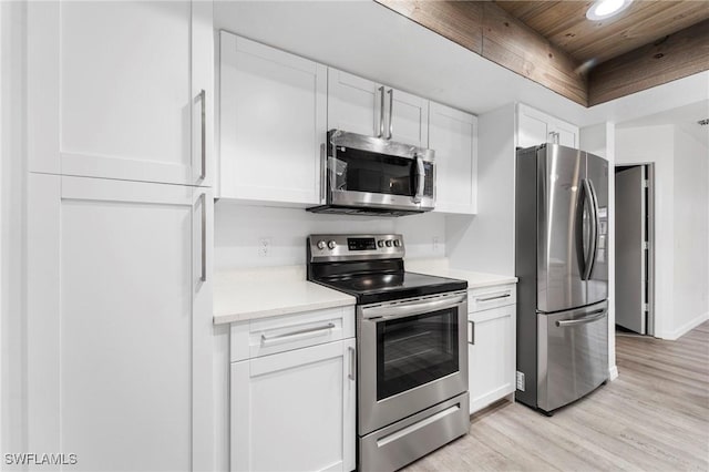 kitchen featuring stainless steel appliances, white cabinetry, a raised ceiling, and light hardwood / wood-style floors