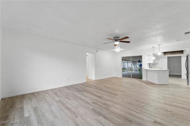 unfurnished living room featuring ceiling fan, light hardwood / wood-style floors, and a textured ceiling