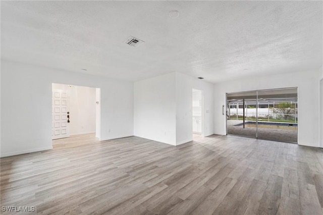 unfurnished room featuring a textured ceiling and light wood-type flooring