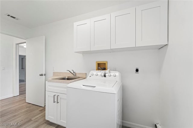 washroom featuring sink, cabinets, light hardwood / wood-style flooring, and washer / dryer