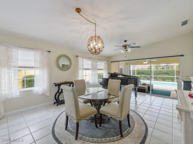 tiled dining space featuring ceiling fan with notable chandelier and vaulted ceiling