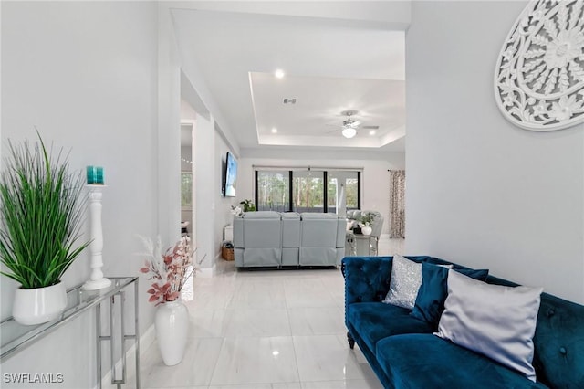 living room featuring washer / dryer, a raised ceiling, and ceiling fan