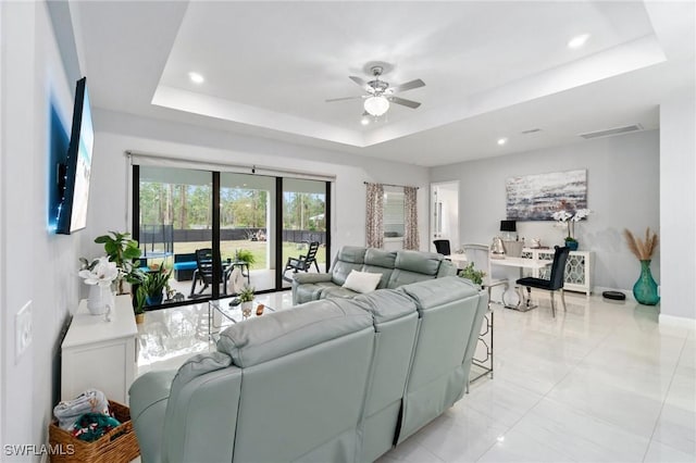 living room featuring a raised ceiling and ceiling fan