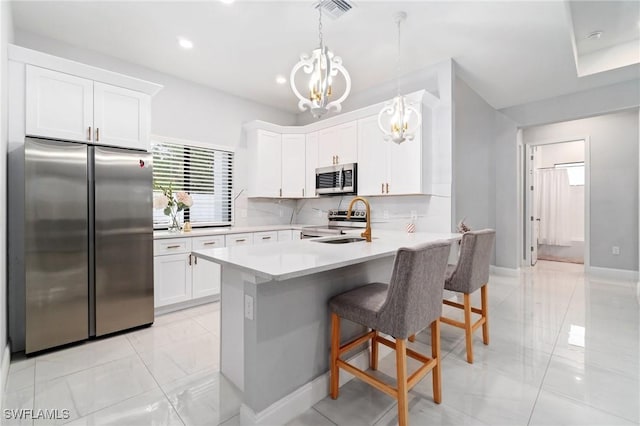 kitchen featuring white cabinetry, stainless steel appliances, sink, and hanging light fixtures