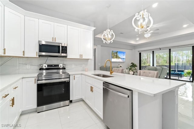 kitchen with sink, hanging light fixtures, kitchen peninsula, and appliances with stainless steel finishes