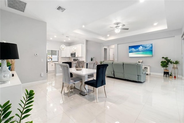 dining area with a tray ceiling and ceiling fan