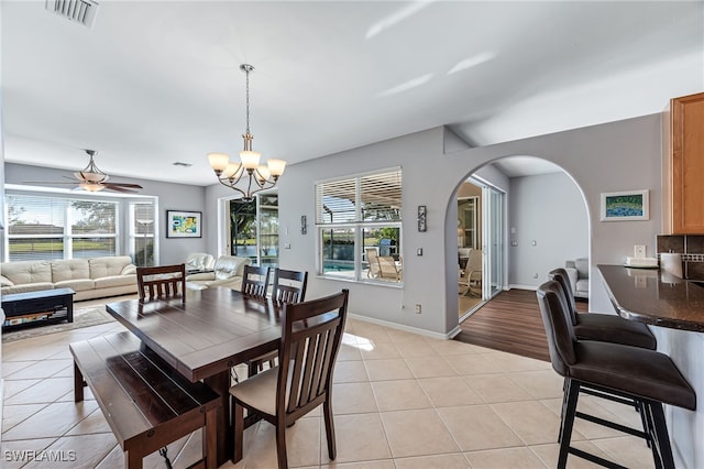 dining area featuring light tile patterned flooring, plenty of natural light, and ceiling fan with notable chandelier