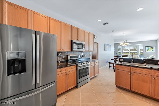 kitchen with light tile patterned floors, appliances with stainless steel finishes, backsplash, hanging light fixtures, and a notable chandelier