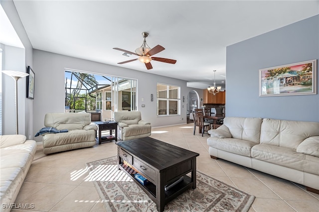 tiled living room with ceiling fan with notable chandelier