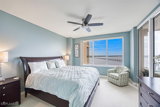 carpeted bedroom featuring ceiling fan and a water view