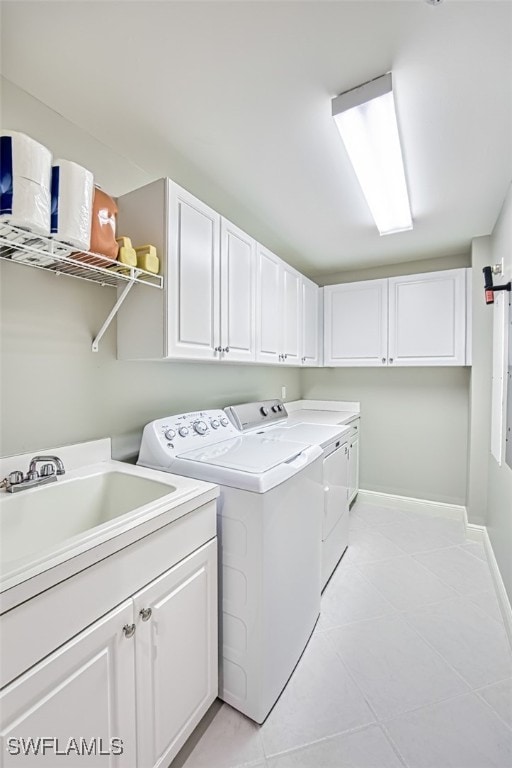 washroom featuring washing machine and dryer, cabinets, light tile patterned floors, and sink