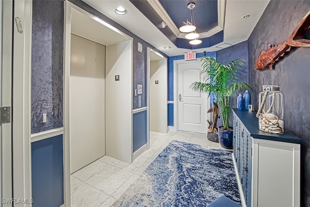 interior space with elevator, ornamental molding, and a raised ceiling