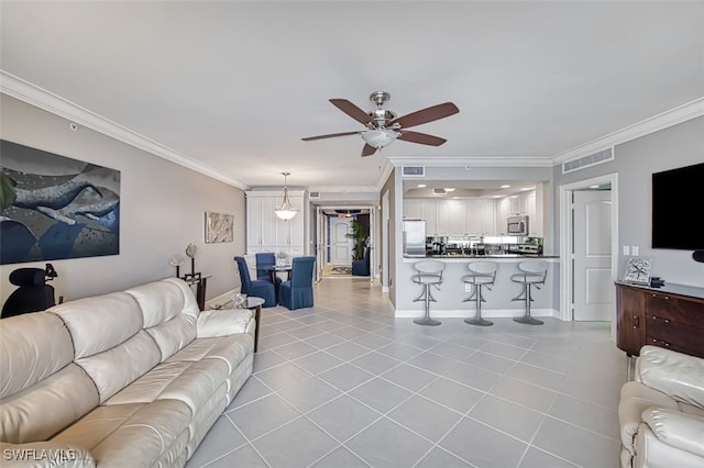 tiled living room with ceiling fan and crown molding