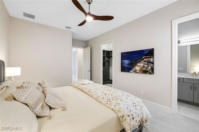 carpeted bedroom featuring a walk in closet, sink, a closet, ceiling fan, and ensuite bathroom