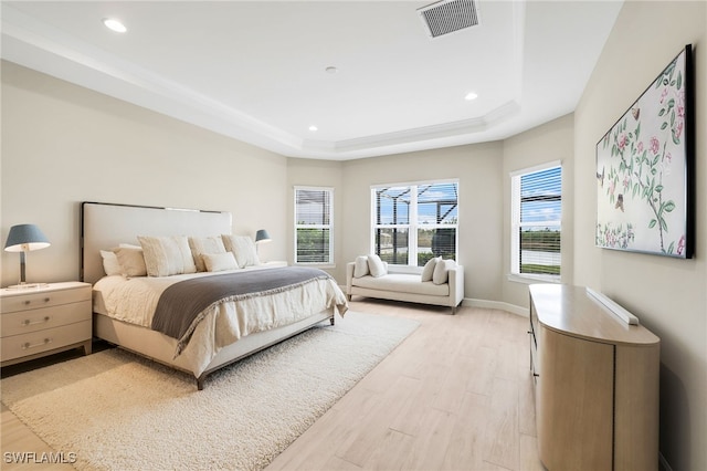 bedroom featuring a tray ceiling and light hardwood / wood-style flooring