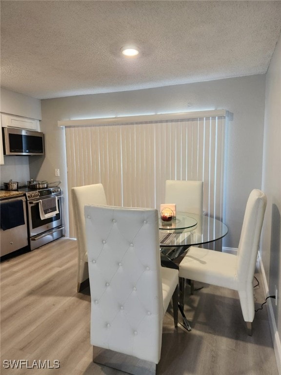 dining space featuring a textured ceiling and light hardwood / wood-style flooring