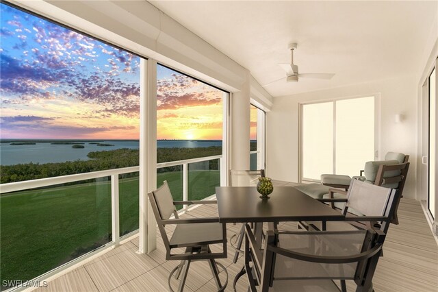 sunroom / solarium with a water view, ceiling fan, and lofted ceiling