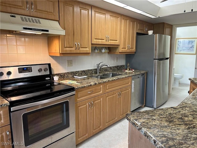 kitchen featuring sink, tasteful backsplash, light tile patterned floors, dark stone counters, and stainless steel appliances