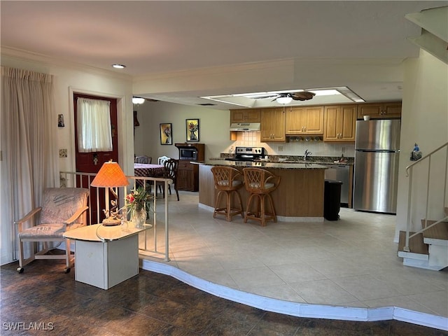 kitchen with tasteful backsplash, appliances with stainless steel finishes, ornamental molding, a kitchen island, and ceiling fan