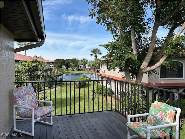 wooden deck with a lawn and a water view