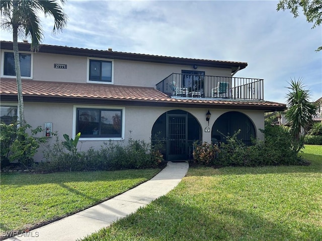 mediterranean / spanish-style home with a balcony and a front lawn