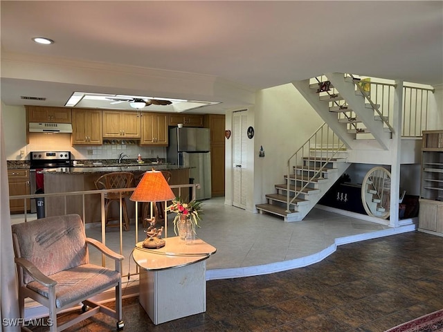 kitchen with sink, a breakfast bar area, ceiling fan, appliances with stainless steel finishes, and decorative backsplash