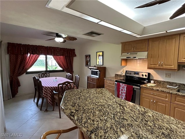 kitchen featuring ceiling fan, appliances with stainless steel finishes, dark stone countertops, backsplash, and light tile patterned flooring