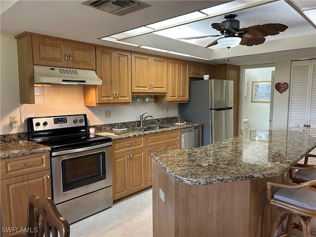 kitchen featuring stainless steel appliances, a breakfast bar area, and dark stone counters