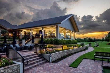 back house at dusk featuring a patio area