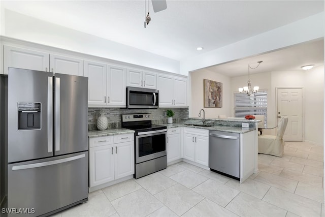 kitchen with sink, kitchen peninsula, stainless steel appliances, light stone countertops, and white cabinets