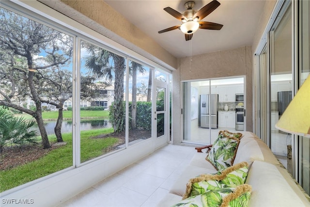 sunroom / solarium featuring a water view and ceiling fan