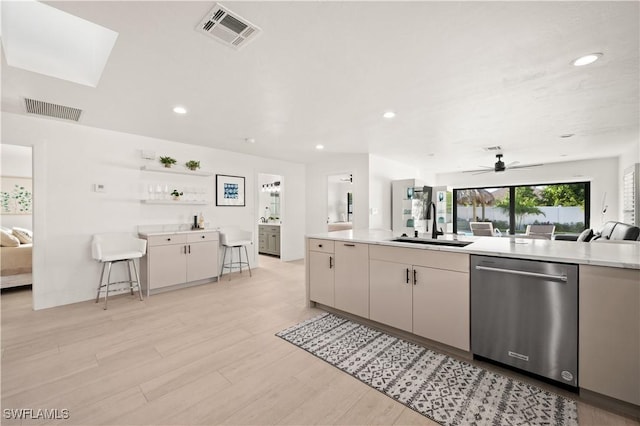 kitchen featuring a kitchen bar, dishwasher, sink, light hardwood / wood-style flooring, and ceiling fan