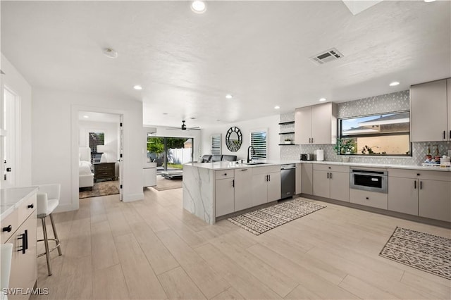 kitchen with appliances with stainless steel finishes, decorative backsplash, sink, kitchen peninsula, and a breakfast bar