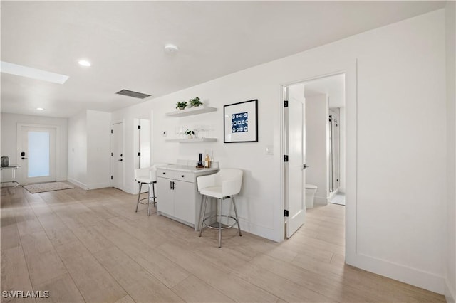 kitchen featuring light wood-type flooring, white cabinets, and a kitchen breakfast bar