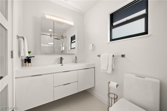 bathroom featuring toilet, a shower with shower door, and vanity