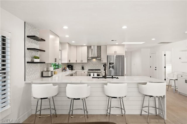 538 106th Ave N, Naples, FL 34108 - kitchen with high quality appliances, open shelves, wall chimney range hood, a peninsula, and light countertops
