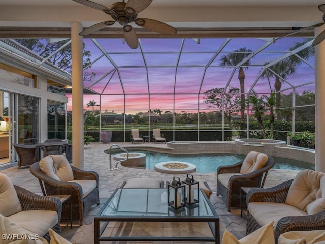 pool at dusk with an in ground hot tub, a patio, an outdoor hangout area, and glass enclosure