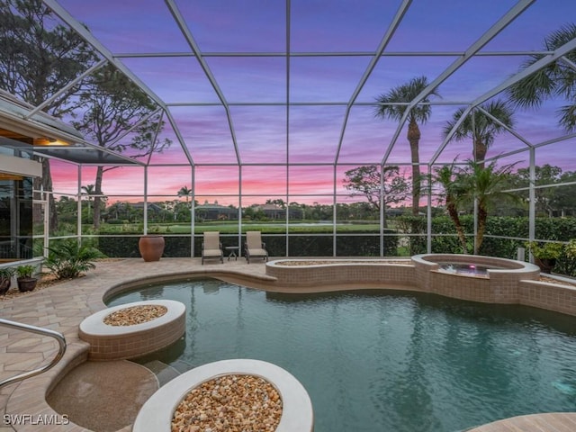 pool at dusk featuring an in ground hot tub, a patio area, and glass enclosure