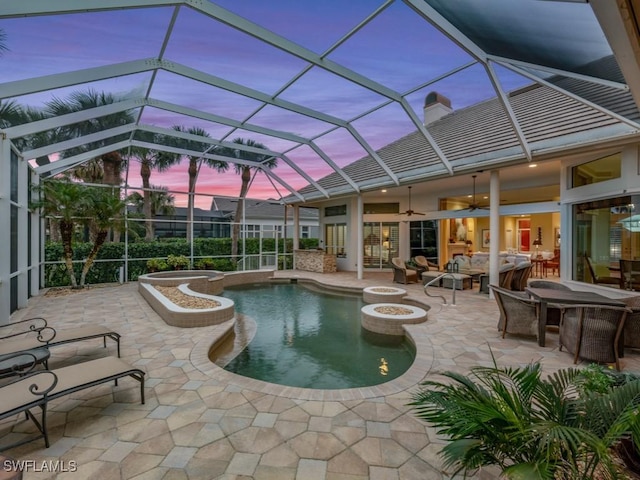 pool at dusk featuring a lanai, a patio, and ceiling fan