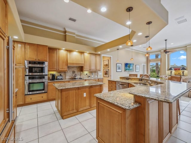 kitchen with hanging light fixtures, wall chimney range hood, light stone counters, and a spacious island