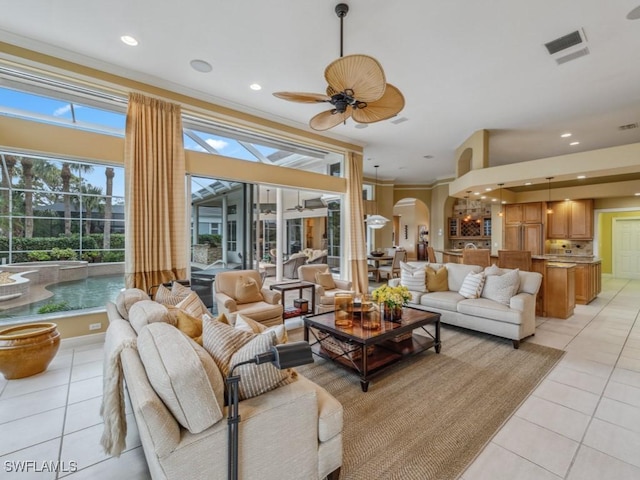 living room with crown molding, ceiling fan, and light tile patterned floors