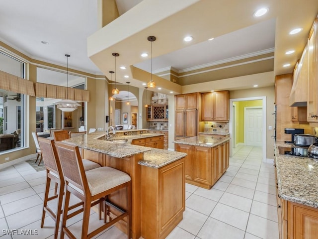 kitchen with ornamental molding, light stone countertops, pendant lighting, and a spacious island