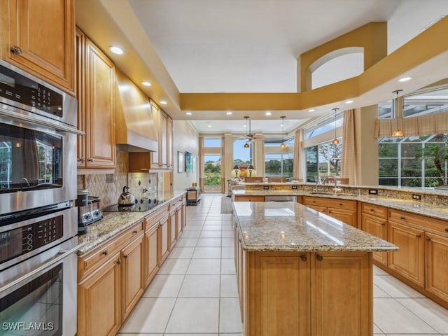 kitchen featuring stainless steel appliances, a kitchen island, light tile patterned floors, and light stone counters